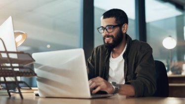 A man looking on his laptop and typing