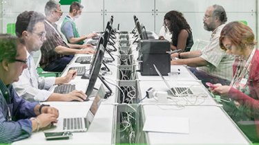 Many people sitting next to computers